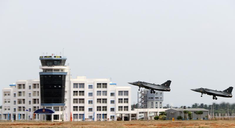 Two Tejas taking off past the air traffic control tower at Sulur